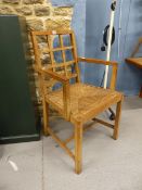 ATTRIBUTED TO HEALS, AN OAK LATTICE BACKED ELBOW CHAIR WITH RUSH DROP IN SEAT.