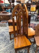 A SET OF THREE OAK CHAIRS WITH TALL GOTHIC ARCHED BACKS ABOVE SOLID SEATS