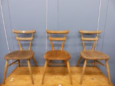 A SET OF THREE ERCOL OAK CHAIRS WITH THE BACK UPRIGHTS FLARING UP FROM THE SOLID SEATS TO SUPPOR