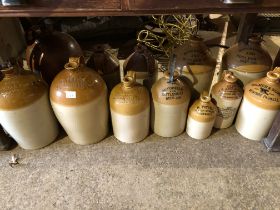 TWELVE VINTAGE STONEWARE FLAGONS.