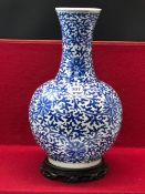 A CHINESE BLUE AND BOTTLE VASE WITH A WOOD STAND, THE PORCELAIN PAINTED OVERALL WITH SCROLLING