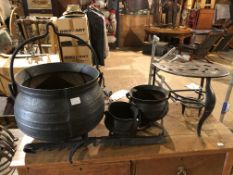 THREE GRADUATED CAST IRON CAULDRONS, A CHIMNEY CRANE AND TWO KETTLE STANDS.