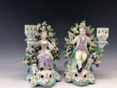 A PAIR OF PATCH MARK DERBY FIGURAL CANDLESTICKS, THE SHEPHERD AND SHEPHERDESS SEATED AMONGST