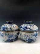 A PAIR OF CHINESE BLUE AND WHITE BOWLS AND COVERS PAINTED WITH FLOWERS, THE RIMS MOUNTED IN BRASS.