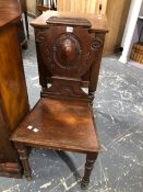 A PAIR OF EARLY VICTORIAN MAHOGANY HALL CHAIRS WITH SHIELD ROUNDELS CENTRAL TO THEIR BACKS