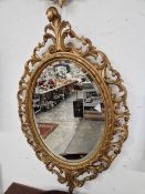 A PAIR OF OVAL MIRRORS IN GILT WOOD FRAMES PIERCED AND CARVED WITH SCROLLING FOLIAGE, POSSIBLY