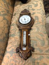 AN OAK CASED ANEROID BAROMETER WITH THE DIAL BELOW A MERCURY THERMOMETER