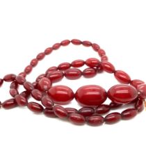 A GRADUATED CONTINUOUS ROW OF CHERRY AMBER BEADS. THE LARGEST BEAD DIAMETER 15.7mm