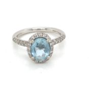 AN 18ct HALLMARKED GOLD BLUE TOPAZ AND DIAMOND RING. THE CENTRAL OVAL TOPAZ IN A RAISED FOUR CLAW