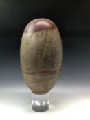 A LARGE INDIAN SHIVA LINGAM STONE OF SOFT GREY COLOUR WITH RED INCLUSION TO TOP AND RED LINE