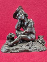 A BRONZE FIGURE OF A BOY TRAVELLER SEATED AMONGST GRAPES WITH HIS EYES CLOSED AND A BOTTLE AND