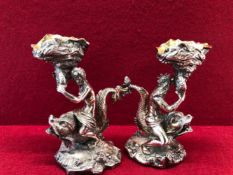 A PAIR OF ELECTROPLATE SALTS IN THE FORM OF A MERMAID AND A MERMAN RIDING DOLPHINS AND HOLDING UP