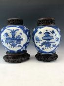 A PAIR OF CHINESE BLUE AND WHITE GINGER JARS, WOOD COVERS AND STANDS, THE PORCELAIN PAINTED WITH