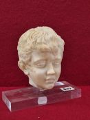 A CARVED WHITE MARBLE HEAD OF A BOY MOUNTED ON A RECTANGULAR PERSPEX PLINTH. W 18 x H 17cms.