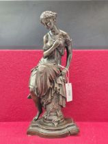 A BRONZE FIGURE OF A CLASSICAL LADY IN LOOSE DRAPERY AND SEATED ON A COLUMN. H 45cms.