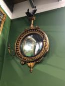 A GEORGE III CONVEX MIRROR WITHIN A BEADED CIRCULAR FRAME CRESTED BY A BLACK SPREAD EAGLE WITH TWO