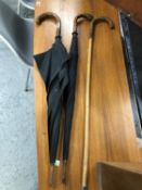 TWO BLACK UMBRELLAS, TWO WALKING CANES AND A LEATHER HANDLED BAMBOO WALKING STICK