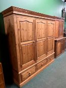 A LARGE PINE THREE DOOR HANGING CUPBOARD WITH THREE BASE DRAWERS.