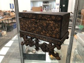 AN INDIAN MINIATURE GILT BLACK LACQUERED COFFER ON STAND