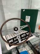 AN E-TYPE JAGUAR STEERING WHEEL, A JAGUAR MASCOT PAPER WEIGHT, A HOT ROD DRYING UP CLOTH TOGETHER