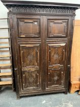 AN ANTIQUE CARVED OAK FLEMISH STYLE TWO DOOR HANGING CUPBOARD