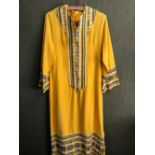 KAFTAN: A YELLOW GROUND KAFTAN DRESS TRIMMED WITH BLUE, GREEN AND WHITE GEOMETRIC BANDS, SLEEVE