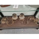 TWO GILT METAL WALL BRACKETS BEARING OIL LAMPS WITH CLEAR GLASS RECEIVERS