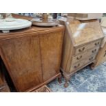 A WALNUT BUREAU ON CARVED CLAW AND BALL LEGS TOGETHER WITH A BOW FRONT TWO DOOR CABINET AND TWO