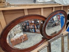 TWO LARGE OVAL FRAMED WALL MIRRORS.
