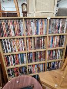 AN EXTENSIVE COLLECTION OF DVDS CONTAINED IN AN OPEN FRONT SHELF UNIT