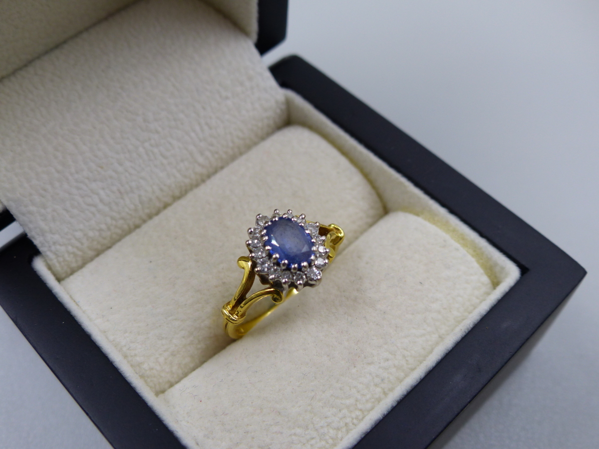 AN 18t HALLMARKED SAPPHIRE AND DIAMOND CLUSTER RING. THE OVAL SAPPHIRE A LIGHT CORNFLOWER BLUE, - Image 2 of 5