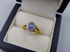 AN 18t HALLMARKED SAPPHIRE AND DIAMOND CLUSTER RING. THE OVAL SAPPHIRE A LIGHT CORNFLOWER BLUE,
