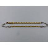 A TWO COLOUR GOLD ANKLE CHAIN, CONSISTING OF PLAIN POLISHED WHITE LINKS, ALTERNATING BETWEEN