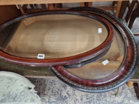 A MAHOGANY FRAMED OVAL MIRROR TOGETHER WITH ANOTHER OVAL MIRROR