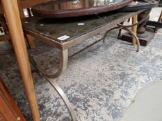 A GLASS TOPPED COFFEE TABLE SUPPORTED ON A METAL BASE