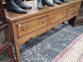 A 19th C. OAK DRESSER BASE WITH THREE MAHOGANY BANDED DRAWERS OVER A CUT WORK APRON AND SQUARE LEGS.