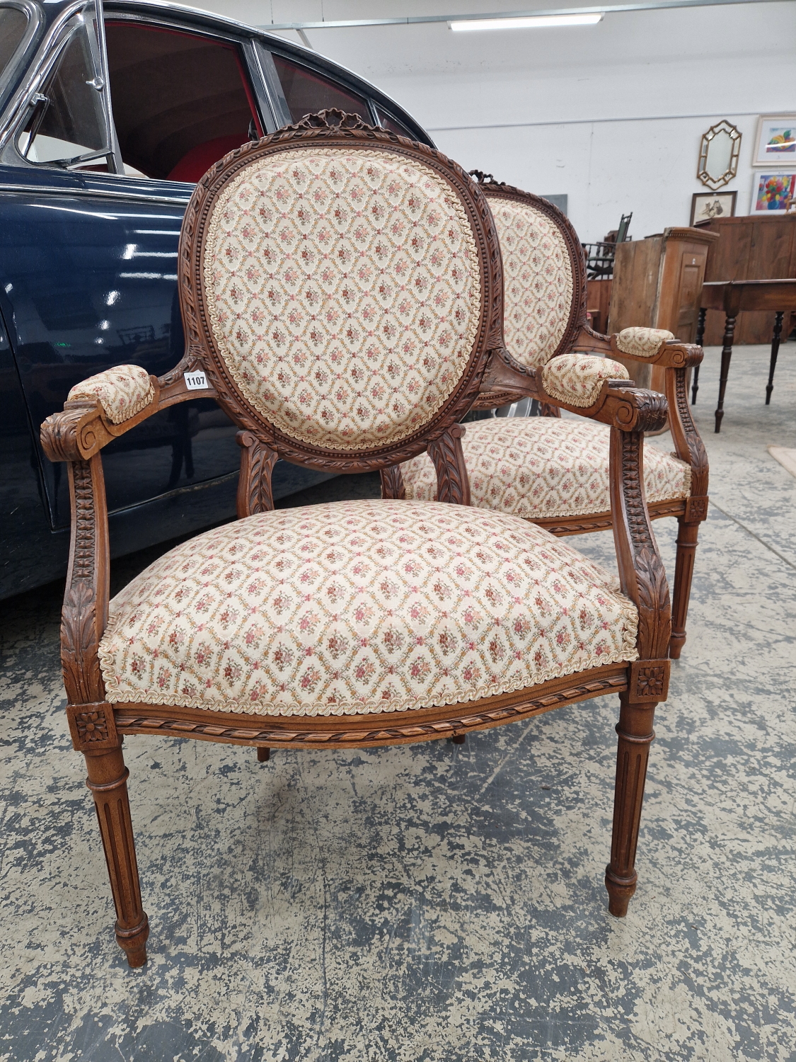 A PAIR OF FRENCH CARVED SHOW FRAME OPEN ARMCHAIRS ON FLUTED LEGS.