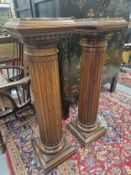 A PAIR OF MOTTLED RED MARBLE TOPPED MAHOGANY FLUTED CYLINDRICAL COLUMNS ON SQUARE FEET. H 115cms.