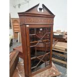 AN ANTIQUE MAHOGANY CORNER CUPBOARD WITH A FOLIATE SCROLL BAND INLAID ABOVE THE GLAZED DOOR