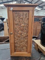 A PINE WALL CUPBOARD, THE DOOR CARVED IN RELIEF WITH A BRANCH OF FRUIT AND ENCLOSING SHELVES