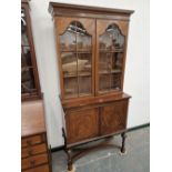 A 1920's WALNUT GLAZED CABINET ON A TWO DOOR BASE WITH BARBERS POLE LINE INLAY, THE TURNED