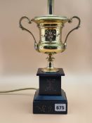 A BRASS TWO HANDLED URN AS A TABLE LAMP SUPPORTED ON A BLACK MARBLE BASE. H 39cms.