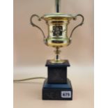 A BRASS TWO HANDLED URN AS A TABLE LAMP SUPPORTED ON A BLACK MARBLE BASE. H 39cms.