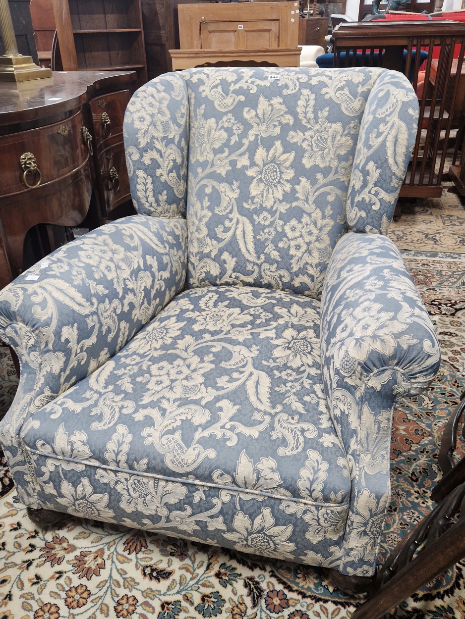 A CONTEMPORARY WING ARMCHAIR UPHOLSTERED IN BLUE DAMASK AND SUPPORTED ON MAHOGANY FRONT BUN FEET