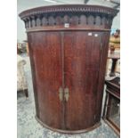 A LARGE GEORGE III OAK TWO DOOR BOW FRONT CORNER CABINET.