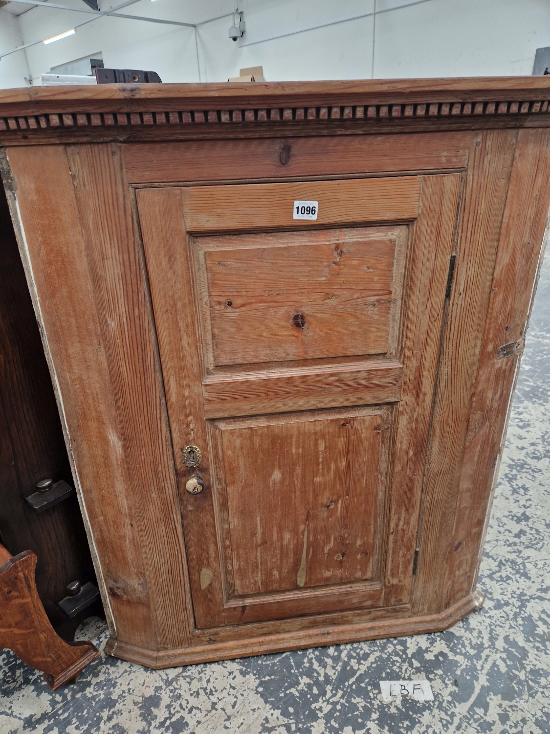 A 19TH CENTURY PINE CORNER CABINET WITH FIELDED PANEL DOOR.