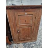 A 19TH CENTURY PINE CORNER CABINET WITH FIELDED PANEL DOOR.