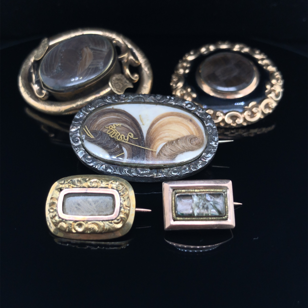 A GROUP OF FIVE ANTIQUE MOURNING BROOCHES. UNHALLMARKED, THREE ASSESSED AS 9ct GOLD. GROSS WEIGHT OF