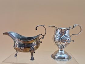 A SILVER CREAM JUG BY CHARLES HOUGHAM, LONDON 1773, EMBOSSED WITH FRUIT TOGETHER WITH A SAUCE BOAT