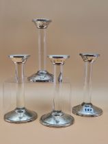 A SET OF FOUR SILVER MOUNTED GLASS COLUMN CANDLESTICKS BY ASPREY, LONDON 2007. H 19cms.